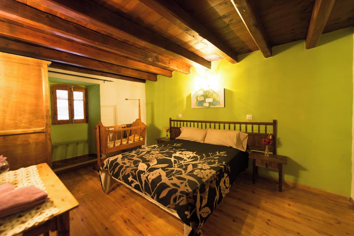 A room with a wooden bed, a nightstand, and a table with a lamp.