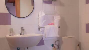 A bathroom with a white sink, toilet, and a green stool.