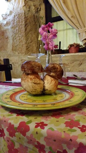 Una mesa con mantel floral, un plato con diseño decorativo y un jarrón con flores rosas.