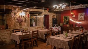 Un'accogliente sala da pranzo in stile rustico, con tavoli e sedie in legno, pareti in pietra e decorazioni tradizionali.