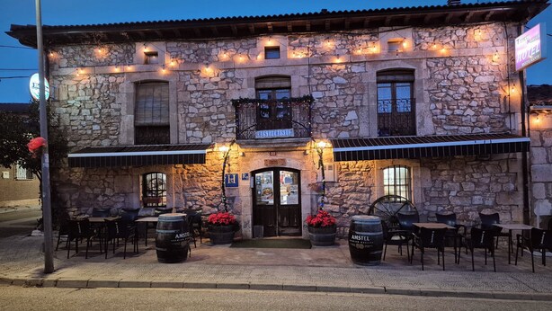 Un edificio in pietra con posti a sedere all'aperto e un'insegna che indica un ristorante.