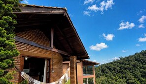 Un edificio de dos pisos con fachada de ladrillo, techo de madera y una hamaca afuera.