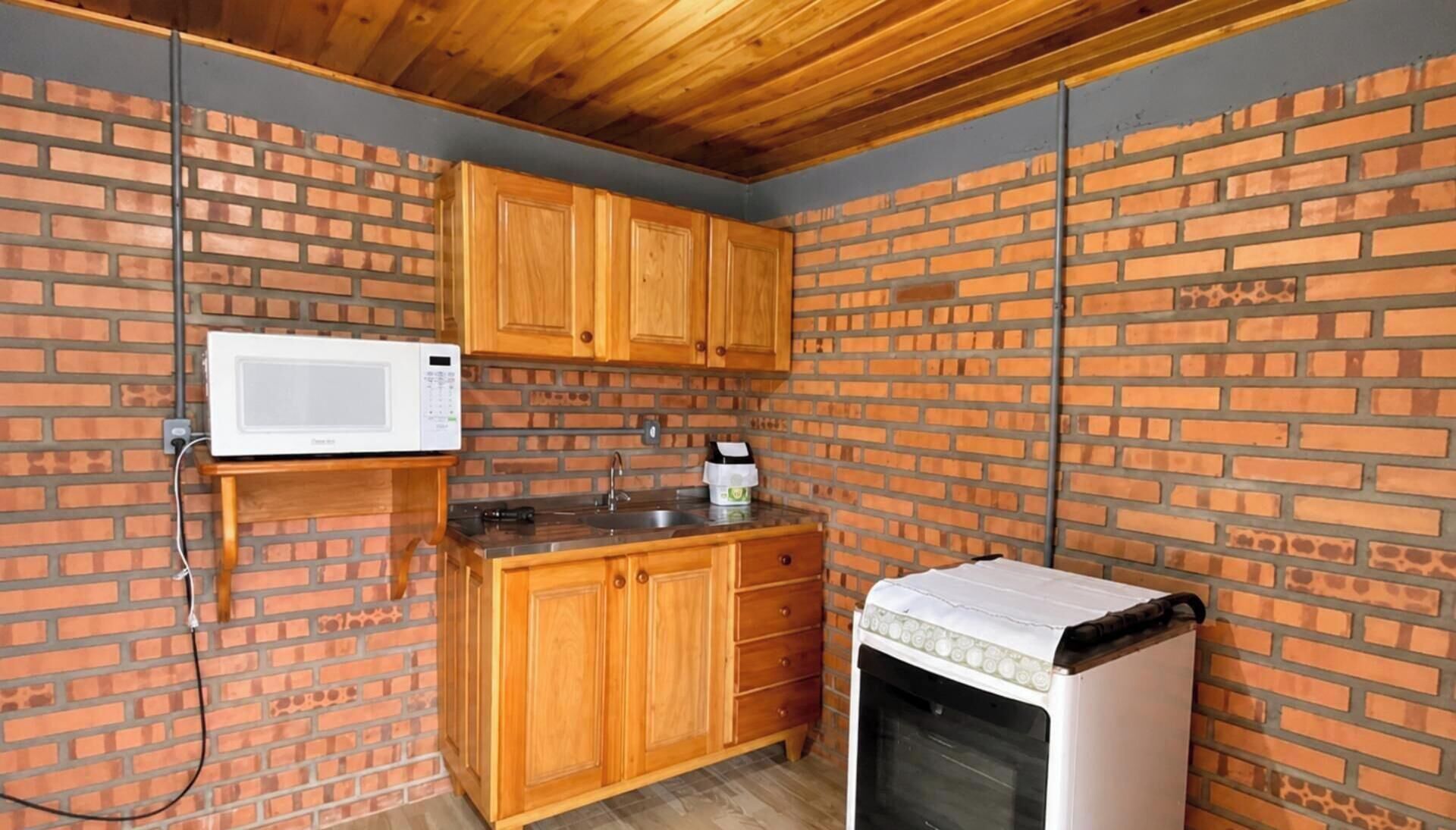 A compact kitchen with wooden cabinets, a microwave, a sink, and a refrigerator.