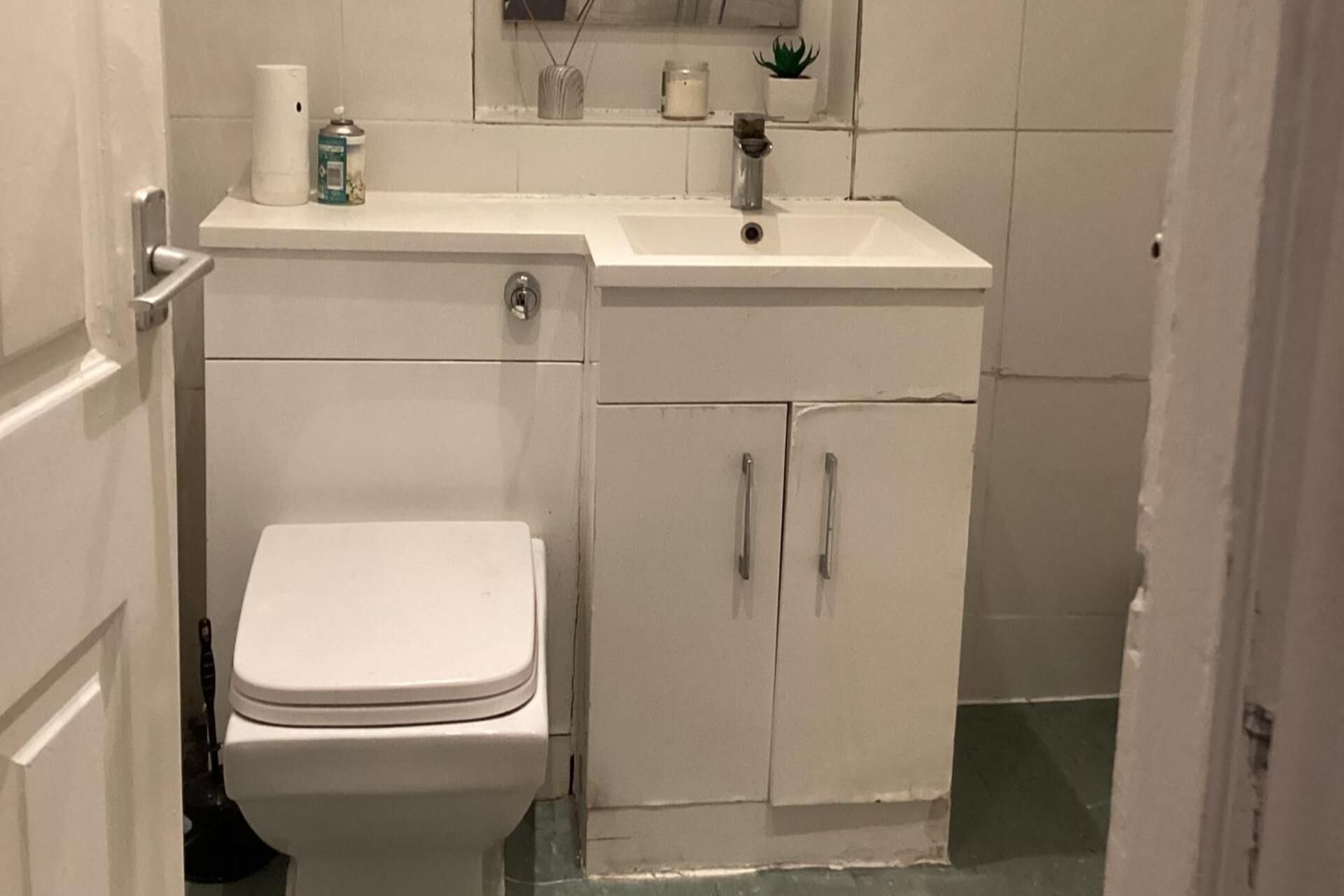 Un bagno con il water, un lavandino e degli armadietti.