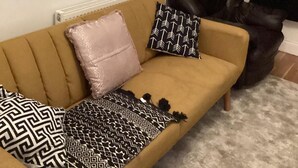 Un sofá color arena con almohadones estampados y una manta decorativa.