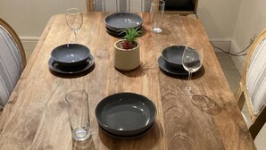 Una mesa de madera con cuatro platos, dos vasos y una pequeña planta en maceta.