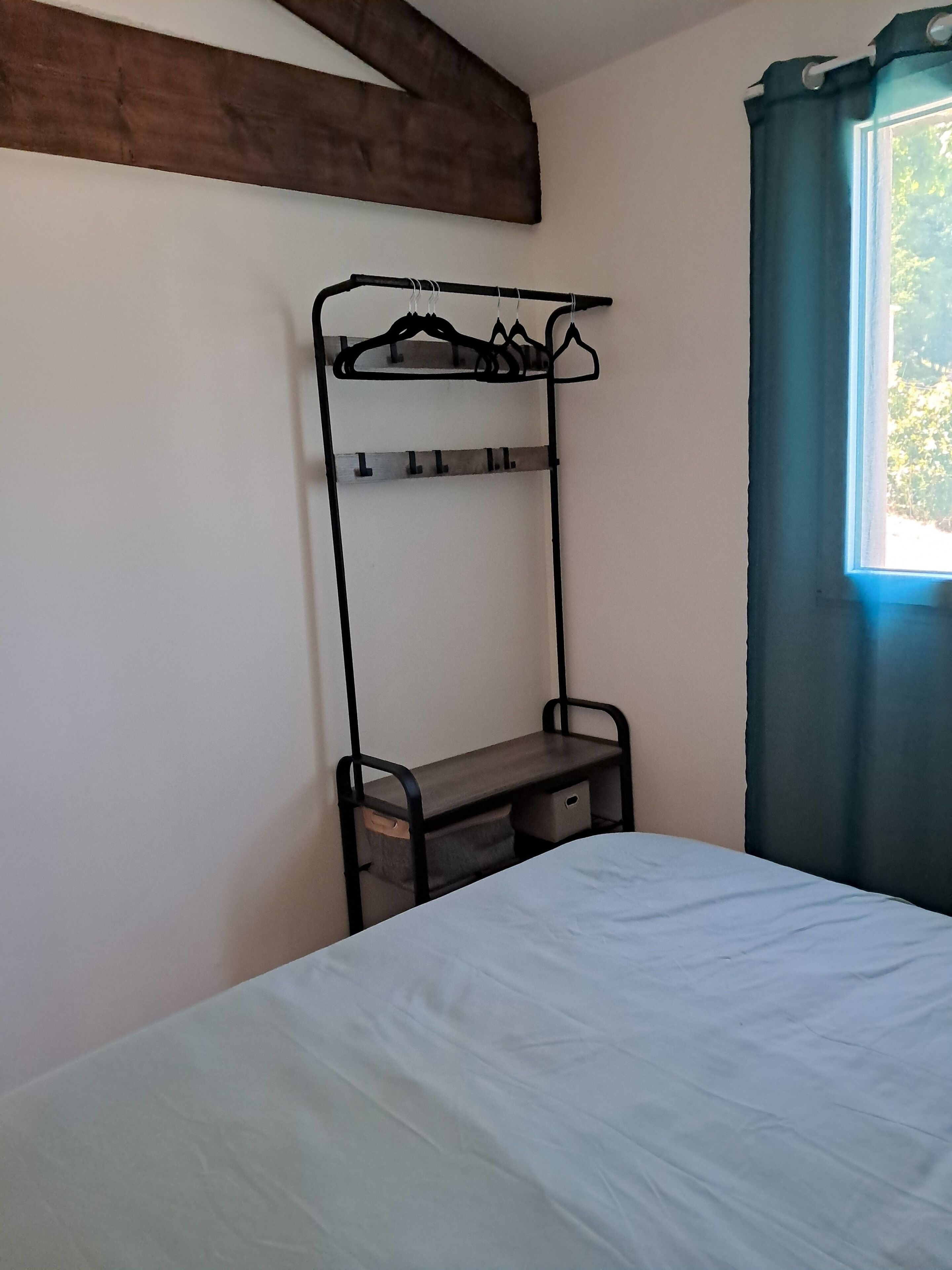 A bedroom with a bunk bed, a small desk with drawers, and a window with curtains.