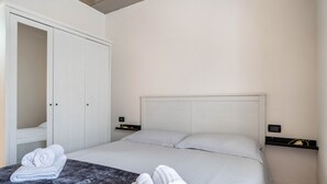 Een hotelkamer met een bed, een kledingkast en een nachtkastje met een lamp.