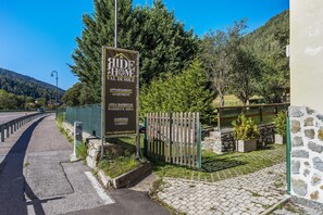 A sign for 'Ride Home Val di Sole' with amenities listed including apartments, barbecue area, and garden.