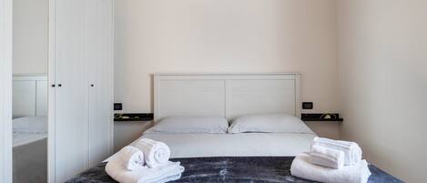 Een hotelkamer met een bed, een kledingkast en een nachtkastje met een lamp.