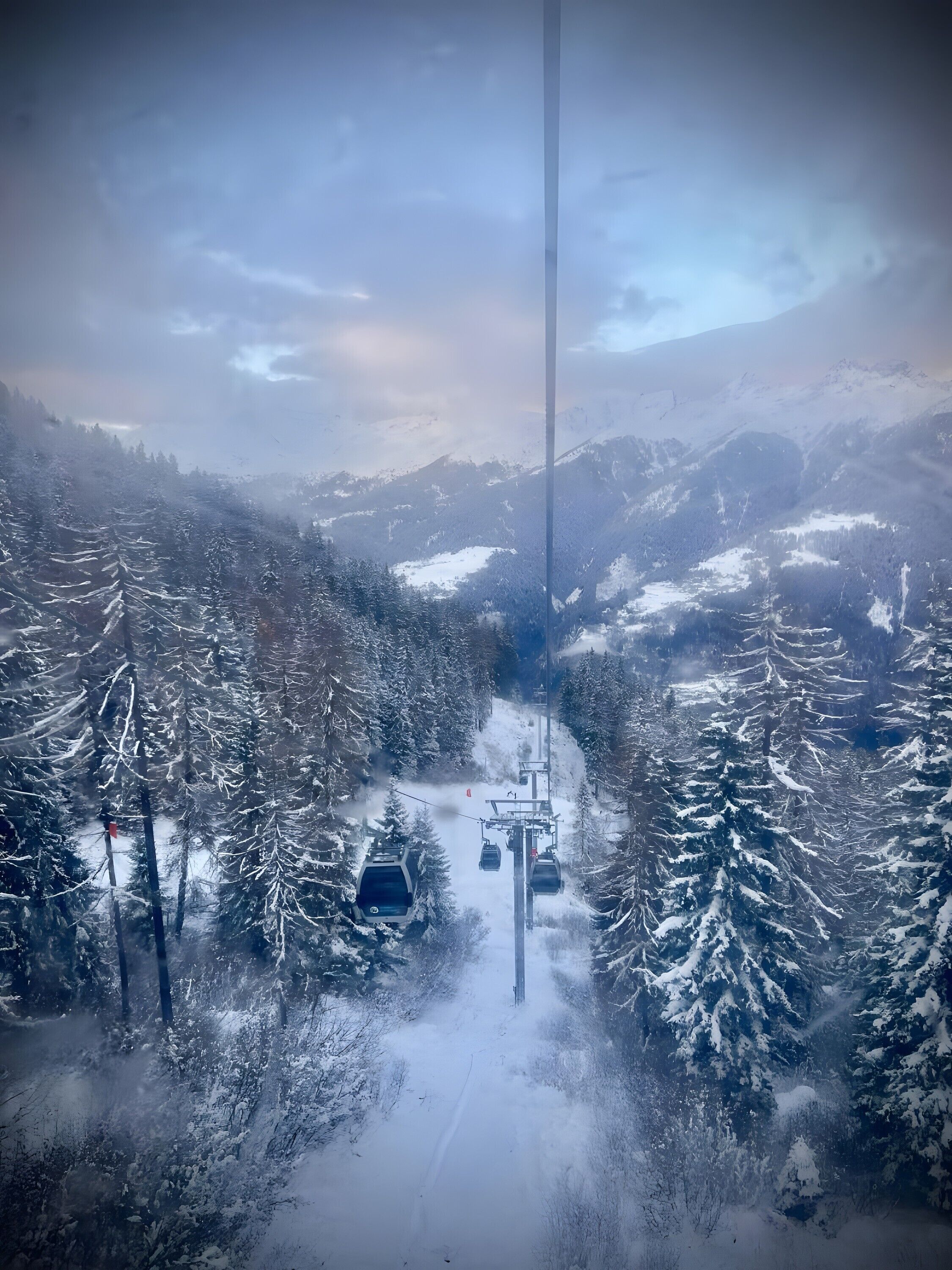 A snowy mountain landscape with a ski lift and trees.
