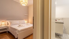 A hotel room with a bed, bedside lamps, a nightstand, and a bathroom with a sink and mirror. - La casa del Vicolo: 2 camere letto, Wi-Fi & A/C (Modena)