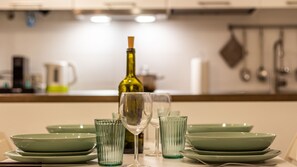 A dining table with green plates, a wine bottle, and glasses. - La casa del Vicolo: 2 camere letto, Wi-Fi & A/C (Modena)
