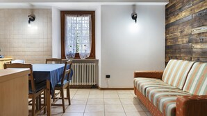 Un comedor con una mesa y sillas, una ventana con cortinas, un radiador y una pared de madera.
