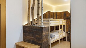 Dormitorio con literas, un banco de madera y una mesita.