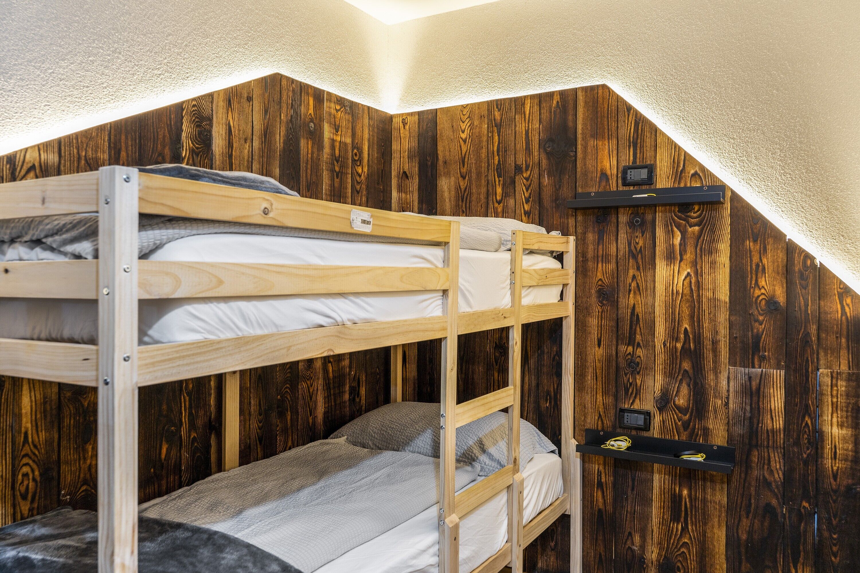 Une chambre avec des lits superposés, des murs en bois et un plafond en pente.