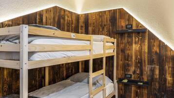 Une chambre avec des lits superposés, des murs en bois et un plafond en pente.