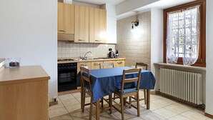 Una cocina con armarios de madera, estufa, lavamanos y una mesa de comedor con sillas.