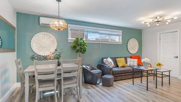 A living room with a dining table, chairs, a sofa, and a coffee table.