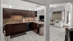 Una cocina moderna con armarios de madera oscura, salpicadero de azulejos y lavavajillas empotrado.