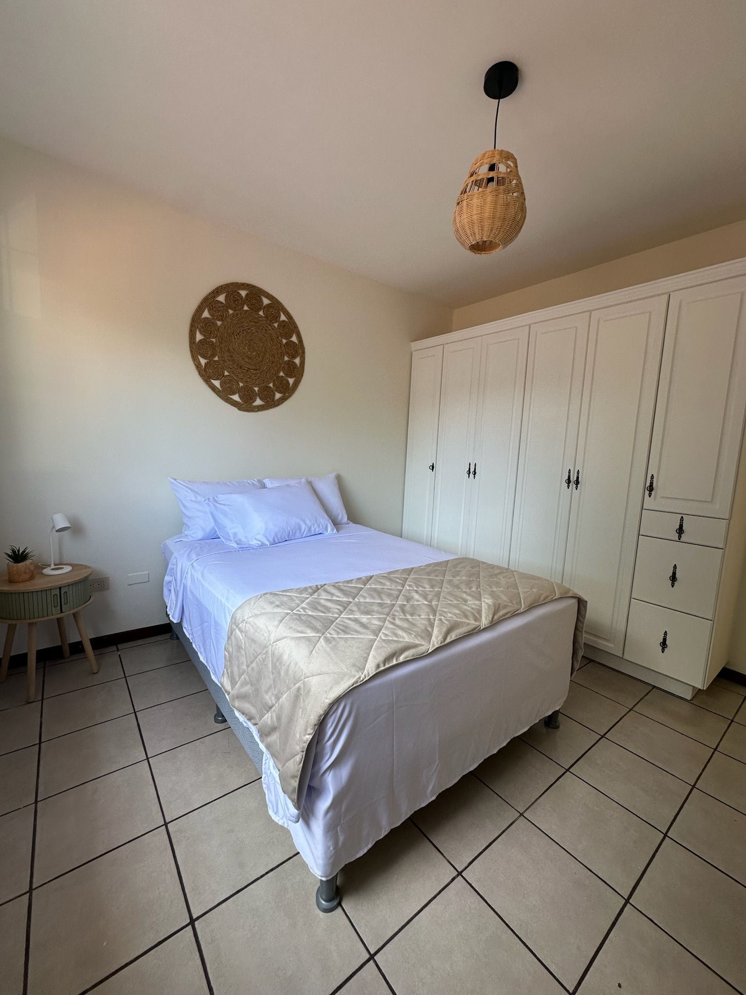 Un dormitorio con cama, armario, decoración en la pared y lámpara colgante.
