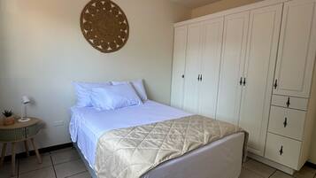 Un dormitorio con cama, armario, decoración en la pared y lámpara colgante.