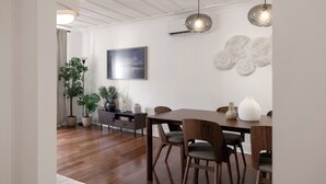 Un comedor moderno con una mesa y sillas de madera, un televisor de pantalla plana en la pared y decoración mural.