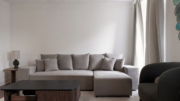 A modern living room with a sectional sofa, a dark wooden coffee table, and a side table with a lamp. - Master Historical Gem in Alfama (Lisboa)