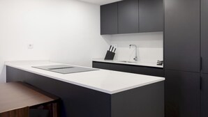 Una cocina moderna con encimera blanca, armarios oscuros y una isla integrada.