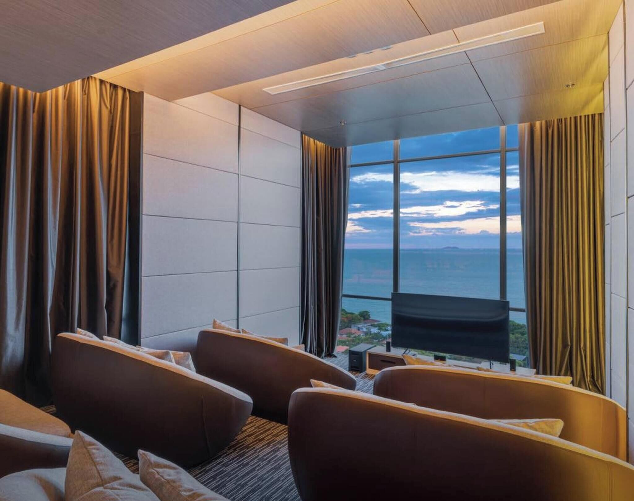 A modern hotel room with a large window, a sofa, and curtains.