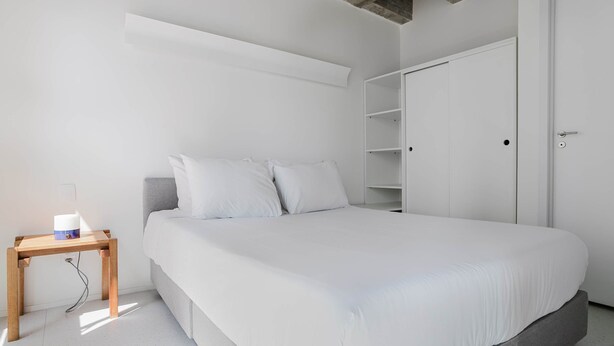 A modern bedroom with a large bed, a bedside table, and a wardrobe. - Eugenio Exclusive Stylish 1 BR in Sao Paulo (São Paulo)