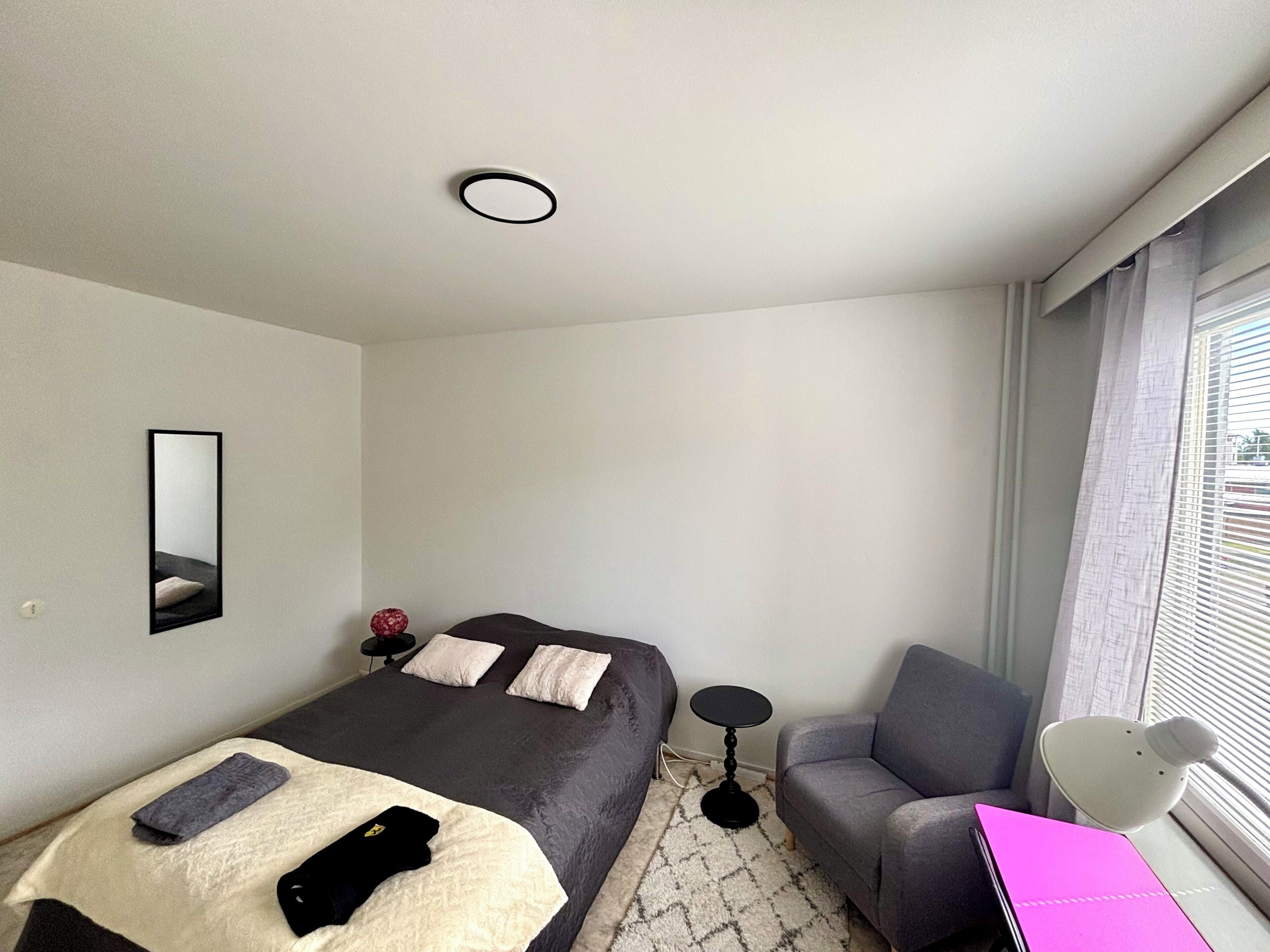 Una habitación de hotel moderna con una cama, un sofá, una mesita y un escritorio con una computadora portátil.