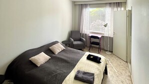 A hotel room with a bed, a chair, a desk, and a window with curtains. - Interesting Kemi Apartment With Peaceful Environment & Free Parking (Kemi)