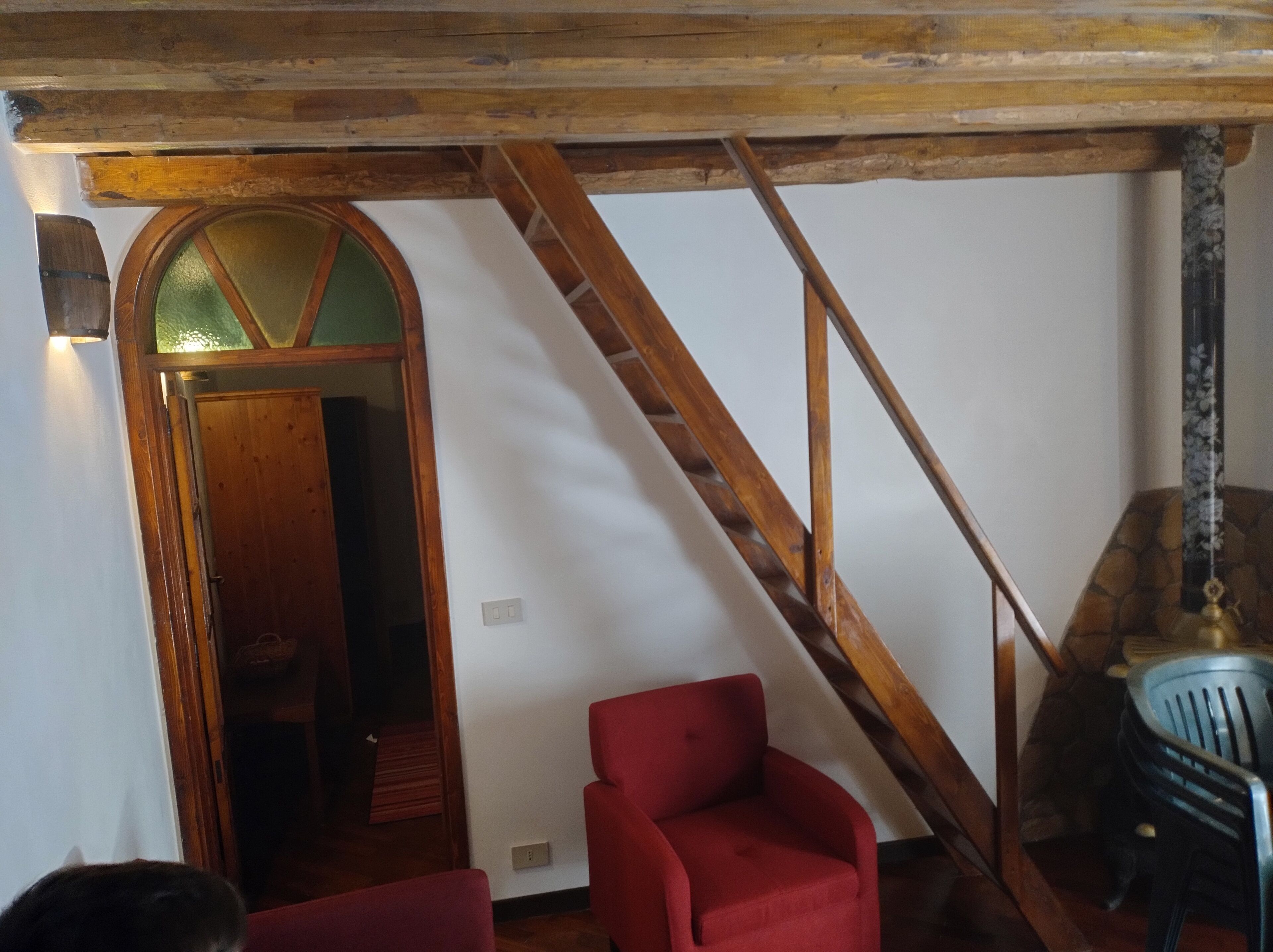 A room with a wooden staircase, a red chair, and a door with a glass panel.