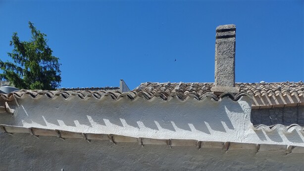 Un bâtiment traditionnel doté d’une façade à motifs, d’une cheminée, d’une porte avec un paillasson et d’une fenêtre avec un volet.