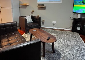 A living room with a brown leather sofa, a matching armchair, a wooden coffee table, and a patterned rug.