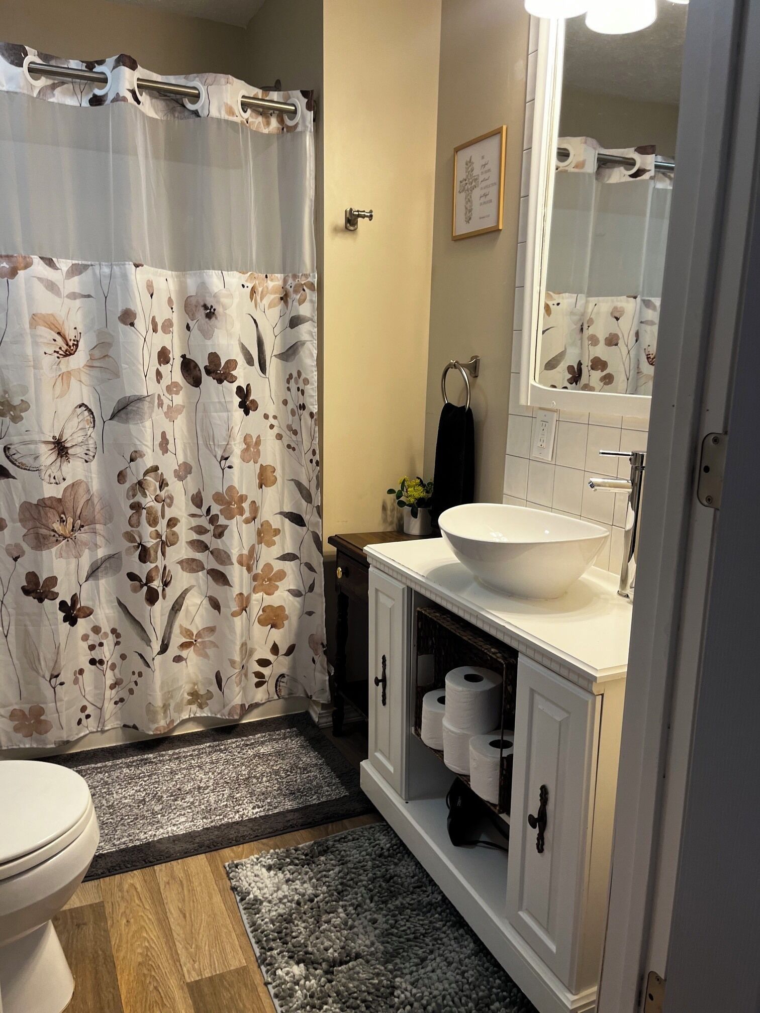 A bathroom with a shower curtain, toilet, sink, and towel rack.