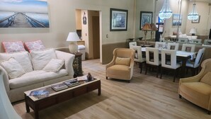Un salon comprenant un canapé, des fauteuils, une table basse et un coin repas avec une table et des chaises.