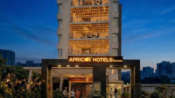 Ein mehrstöckiges Hotel mit modernem Design, das einen markanten Eingang und eine Beschilderung mit dem Schriftzug 'APRICOT HOTELS' zeigt.