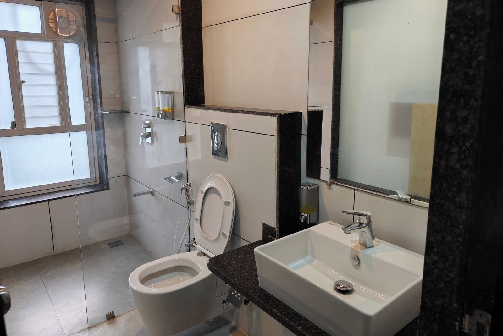 Une salle de bain moderne équipée de toilettes, d’un lavabo et d’un miroir.