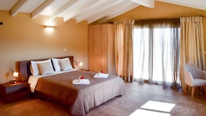A bedroom with a large bed, a nightstand, a chair, and a window with curtains. - Pantokrator Private Pool Gem - Lux Villa in Corfu (Corfu)
