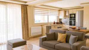 A modern living room with a sofa, ottoman, and coffee table. There is a kitchen area with appliances and a dining table. - Pantokrator Private Pool Gem - Lux Villa in Corfu (Corfu)
