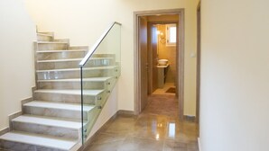 Una escalera con barandillas de vidrio que lleva a un baño.