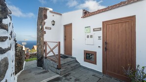 Un edificio costiero con muro in pietra, cancello in legno e vista sul mare.