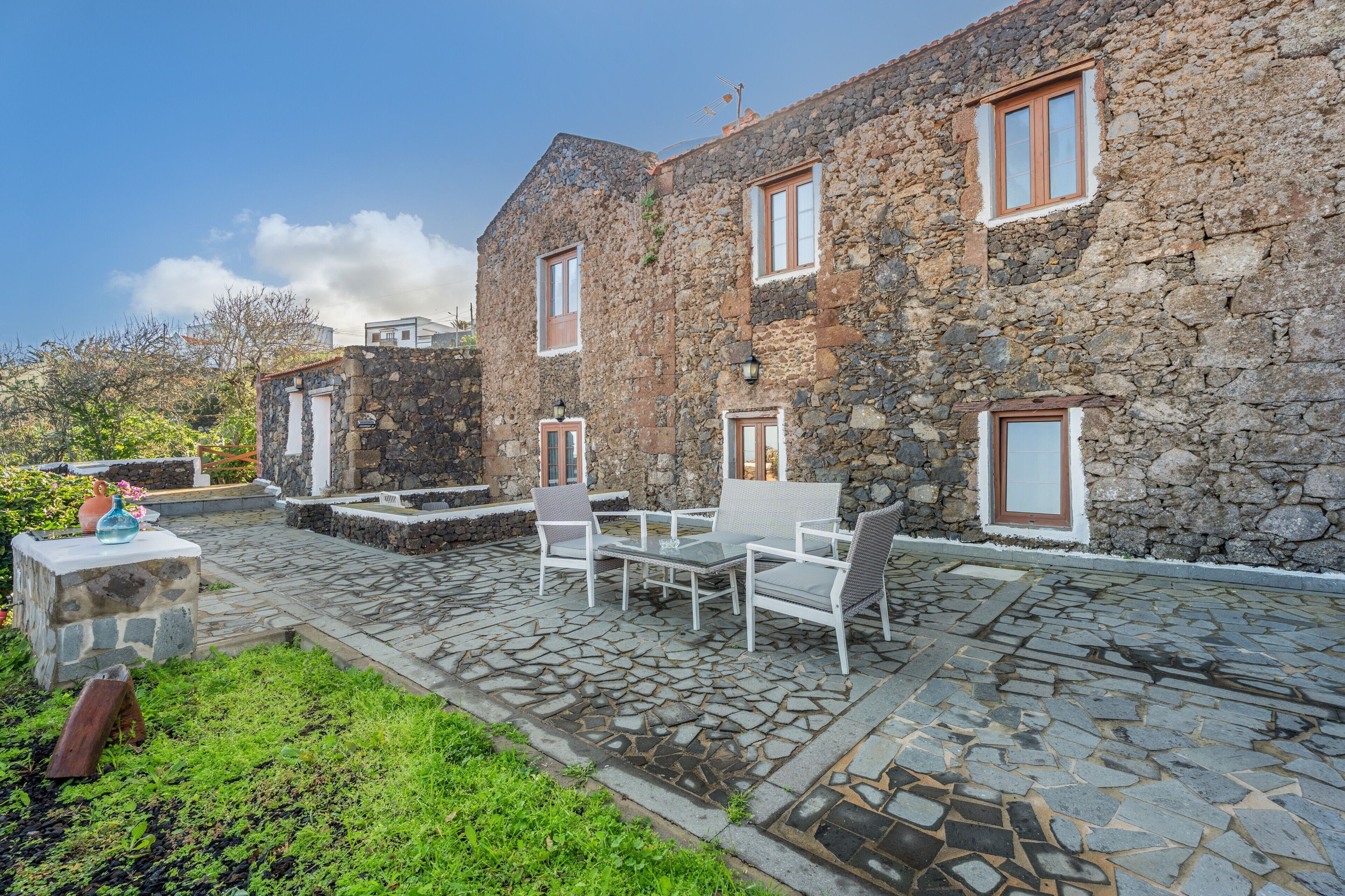 Un bâtiment en pierre doté d’un patio, de sièges en plein air et d’un chemin en pierre.