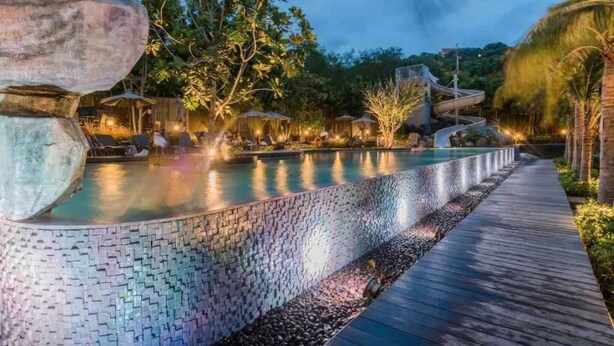 A pool with a tiled edge, a wooden deck, and a waterfall feature. - Sea View High Floor 2 Bed Room-excellent Location (Pattaya)