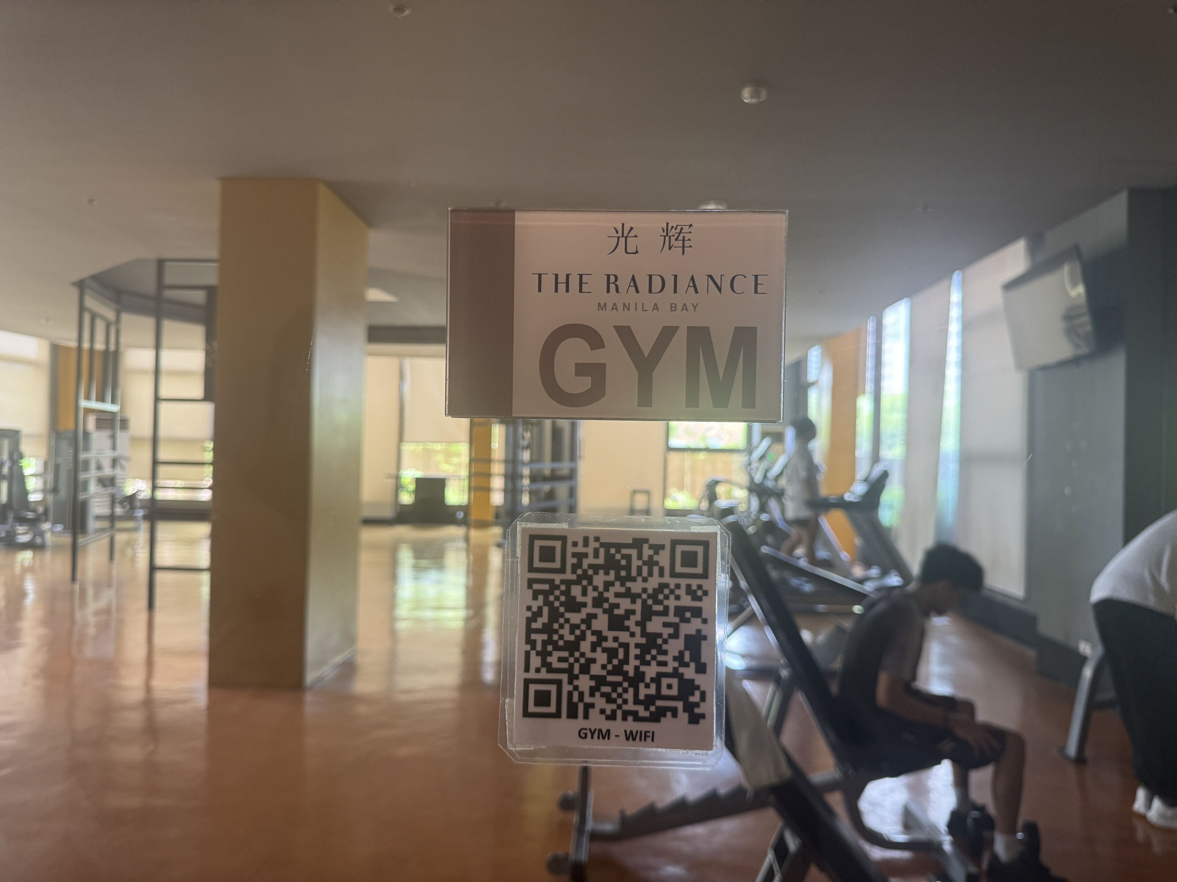 Une enseigne de salle de sport avec un code QR et le texte : « THE RADIANCE GYM – MANILLE BAY ».