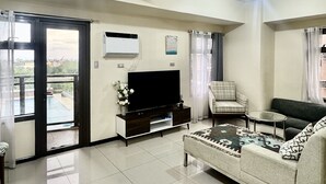 Un salon moderne doté d’un téléviseur à écran plat, d’un canapé, d’une table basse et d’une porte-fenêtre donnant sur un balcon.
