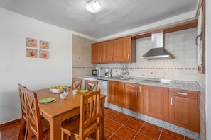 A kitchen with wooden cabinets, a granite countertop, and a dining table with chairs.