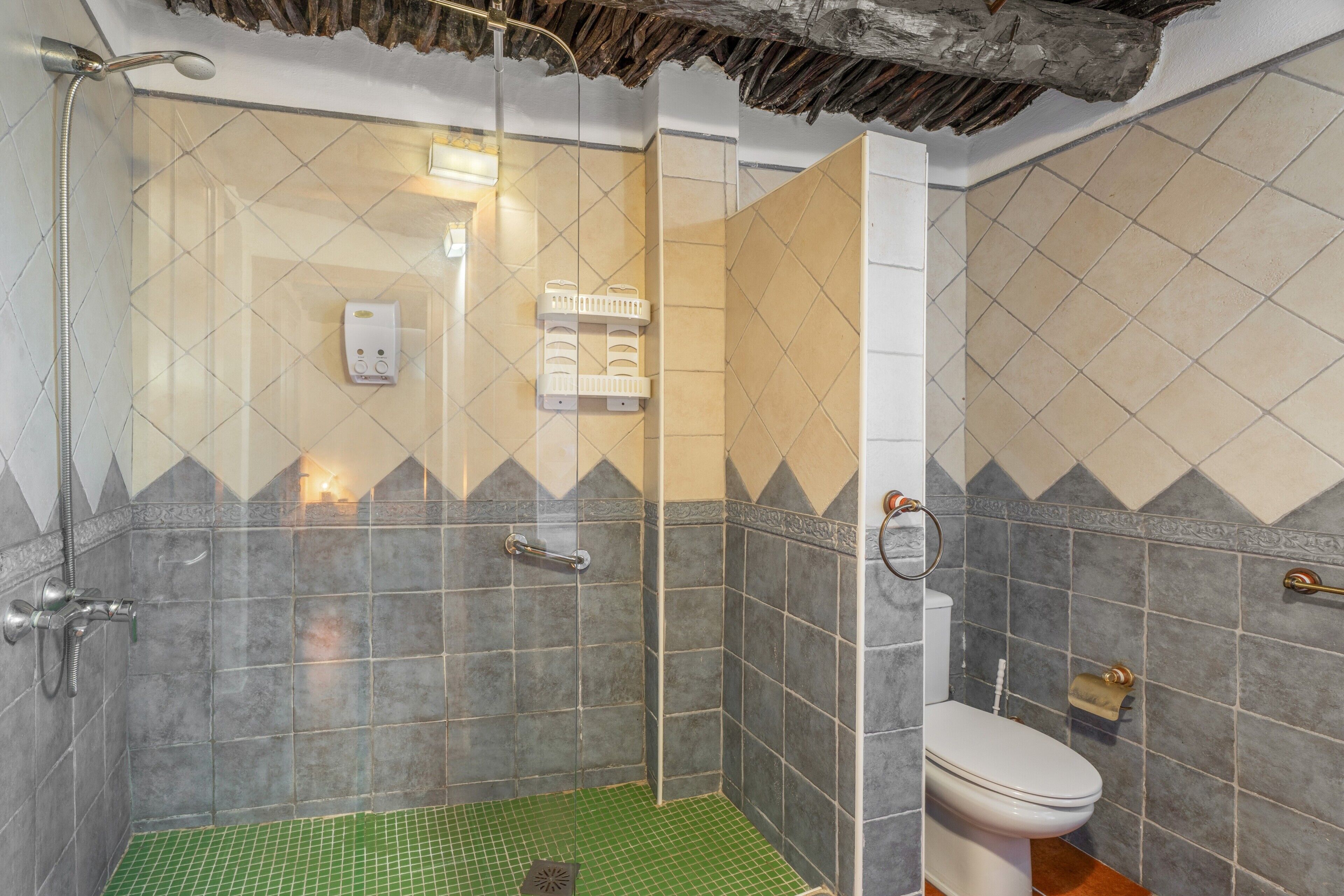 Un bagno con doccia, WC e pavimento piastrellato in verde.